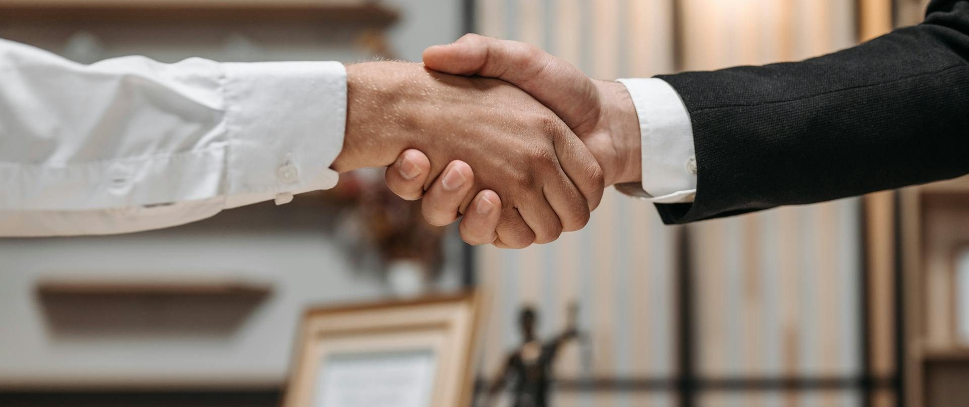Fotografía a color del detalle de dos hombres dándose la mano
