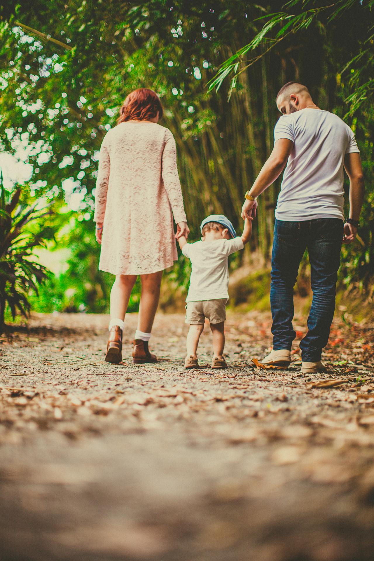 Fotografía a color de unos padres con su hijo pequeño todos de espaldas