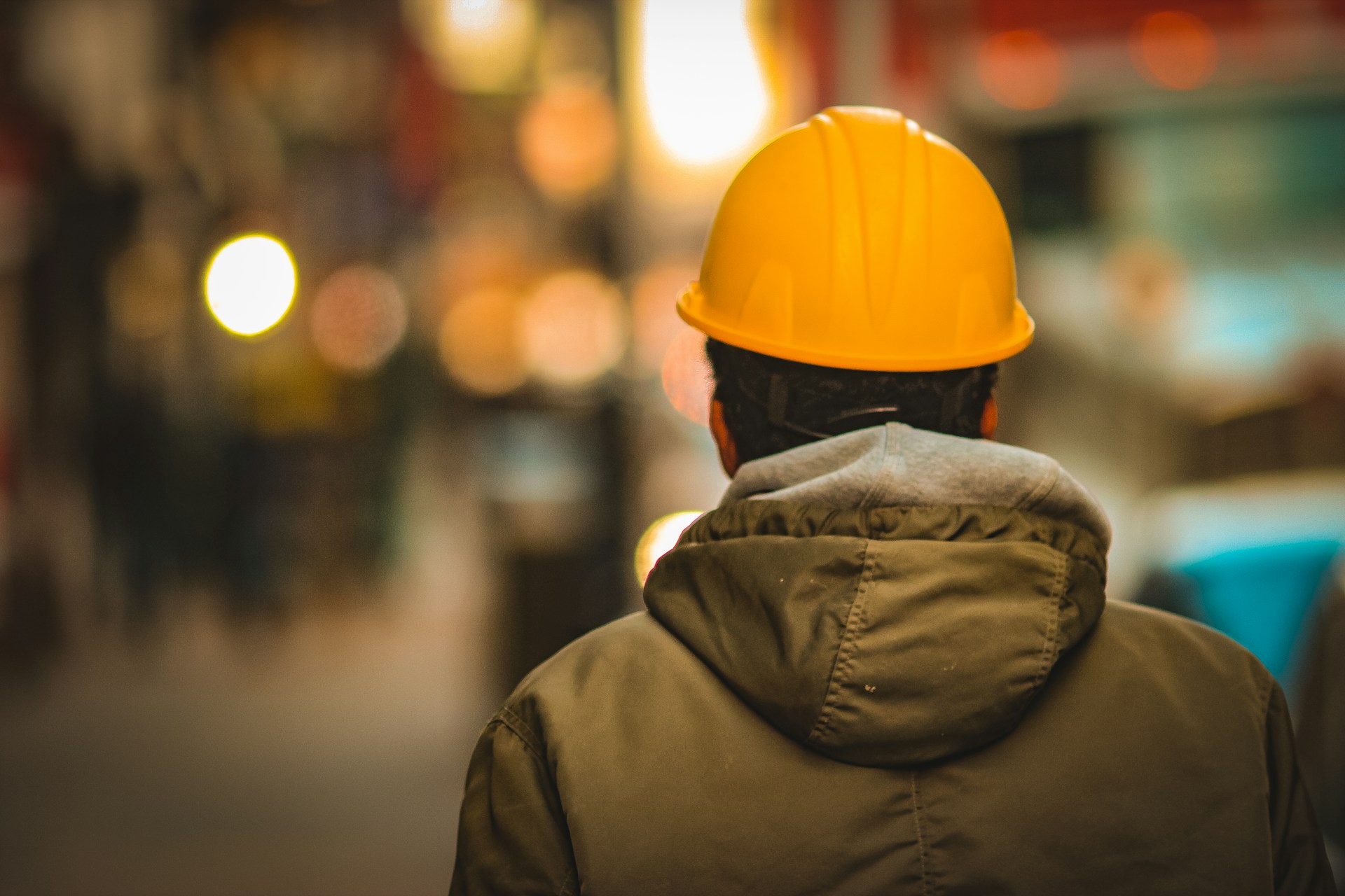 Fotografía a color de un trabajador con casco de espaldas
